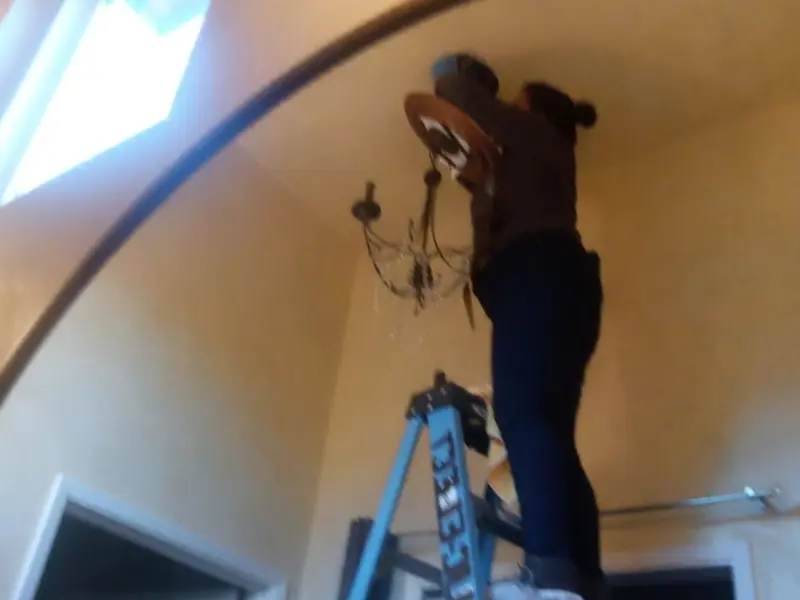 Electrician installing a chandelier in a Wynne residence